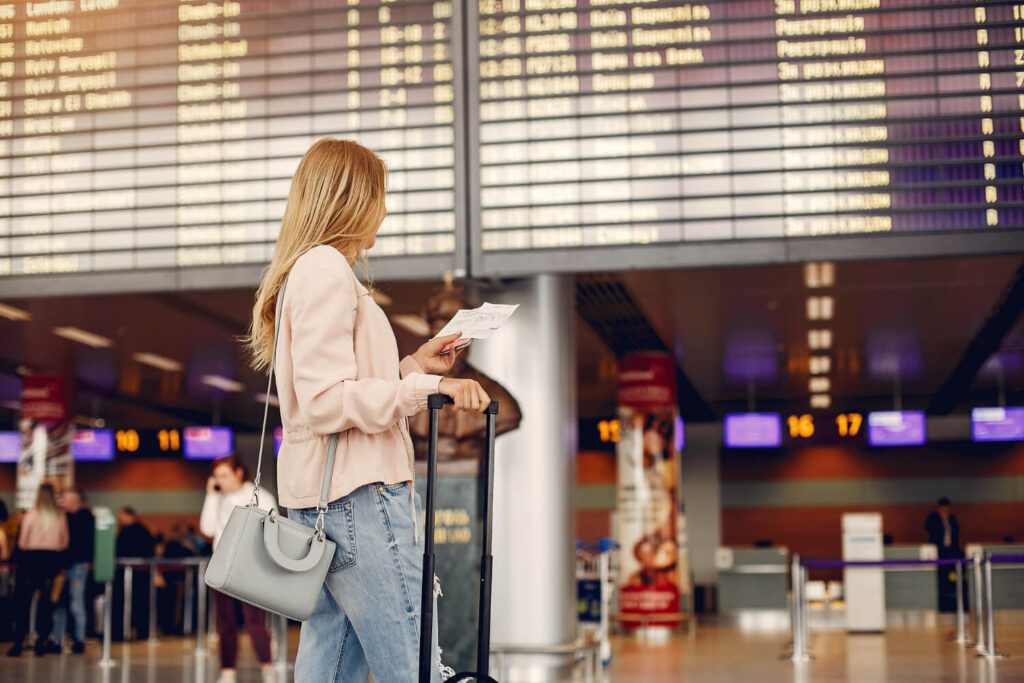 kobieta, która jest na lotnisku pierwszy raz i sprawdza tablicę odlotów